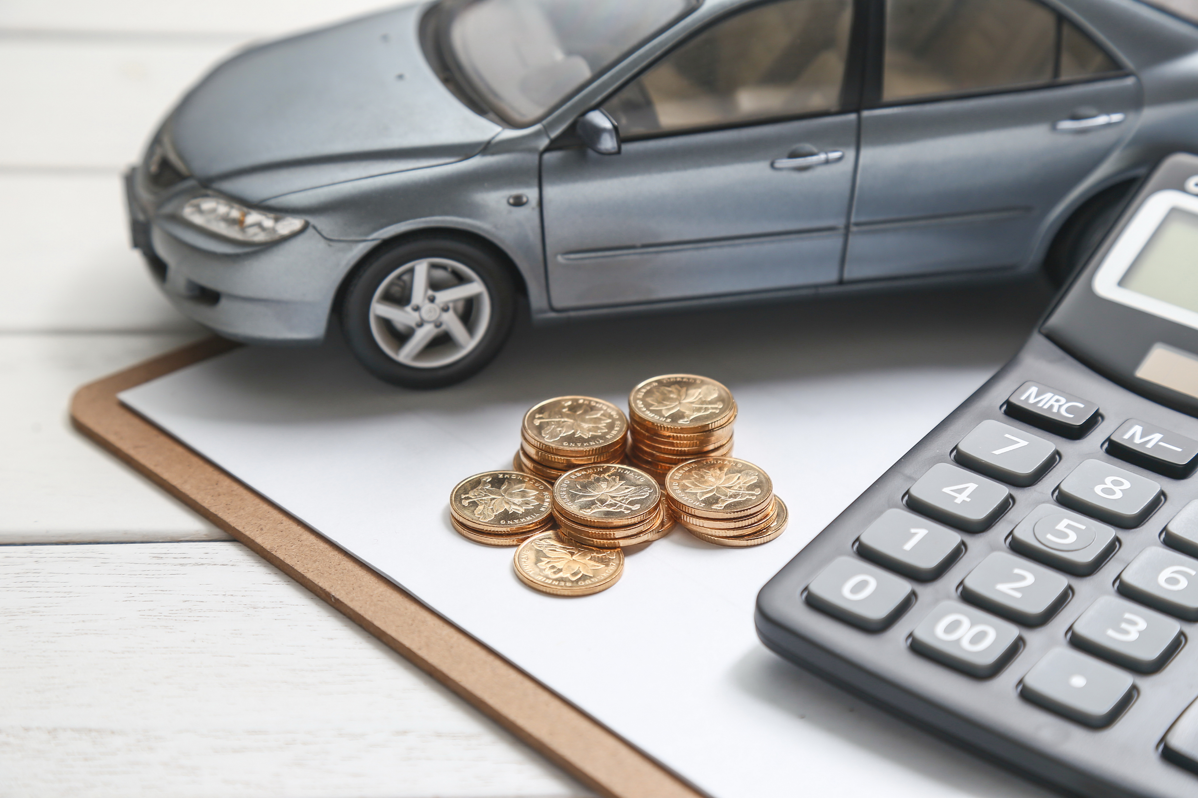 Toy car on documents with calculator and coins